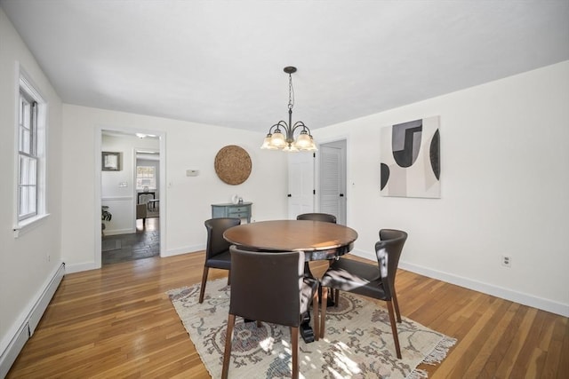 dining area featuring light wood finished floors, baseboards, baseboard heating, and a chandelier