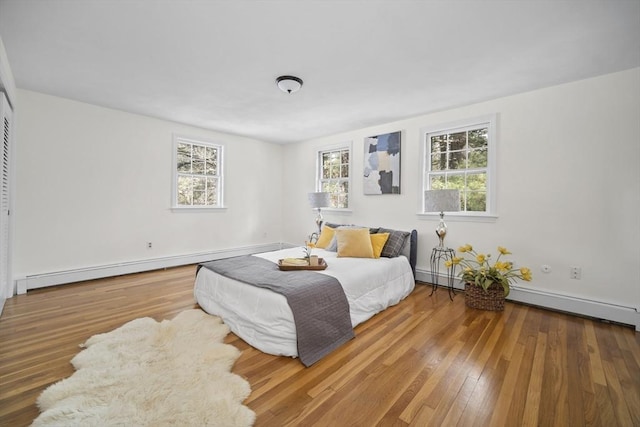 bedroom with baseboard heating and hardwood / wood-style flooring