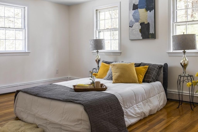 bedroom featuring a baseboard heating unit, baseboards, and wood finished floors