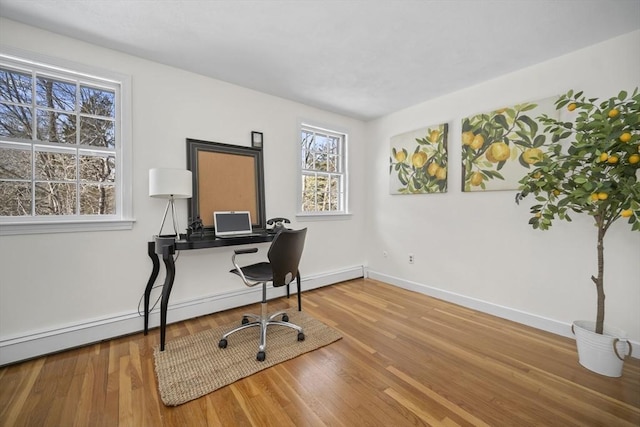 office area featuring a baseboard heating unit, baseboards, and wood finished floors