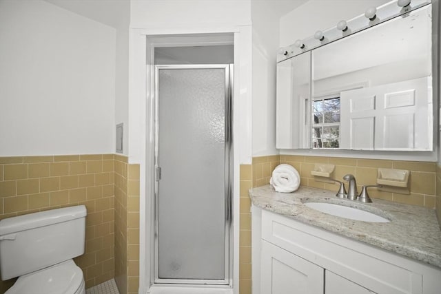 full bathroom with a wainscoted wall, tile walls, toilet, a stall shower, and vanity