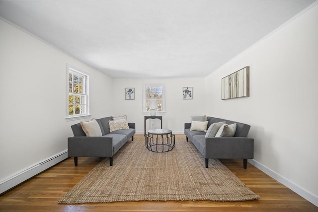 living area with a healthy amount of sunlight, baseboard heating, and wood finished floors