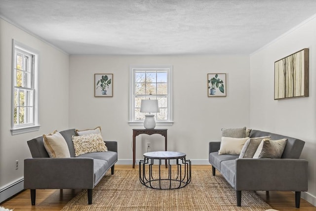 living area featuring baseboards, a textured ceiling, baseboard heating, and wood finished floors