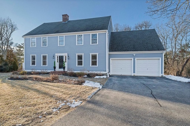 colonial inspired home with a front lawn and a garage