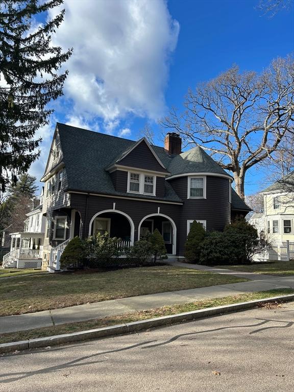 shingle-style home featuring a chimney and a front lawn