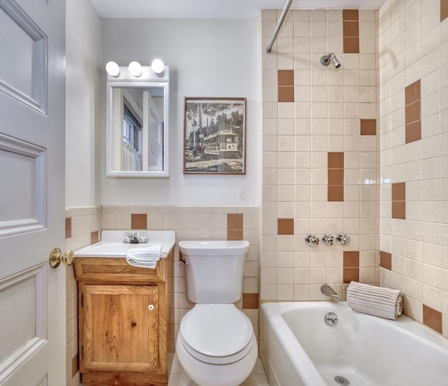 full bath featuring toilet, a wainscoted wall, bathtub / shower combination, vanity, and tile walls