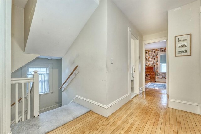 hallway featuring hardwood / wood-style flooring, baseboards, a wealth of natural light, and an upstairs landing