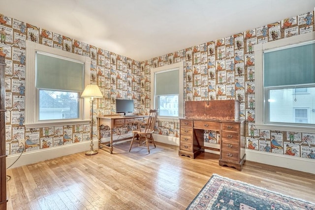 home office featuring wallpapered walls, baseboards, and hardwood / wood-style flooring