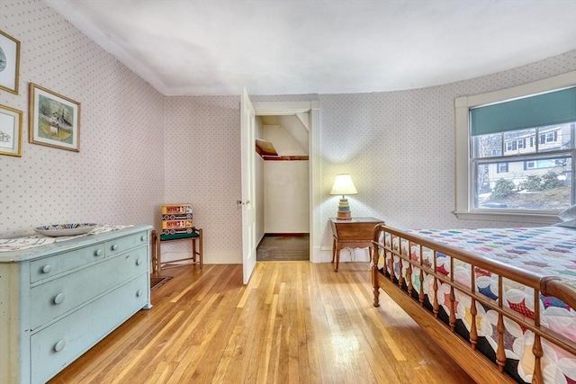 bedroom featuring light wood-style flooring, baseboards, and wallpapered walls