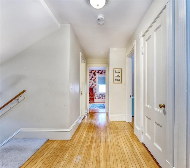 corridor featuring light wood-style flooring and baseboards