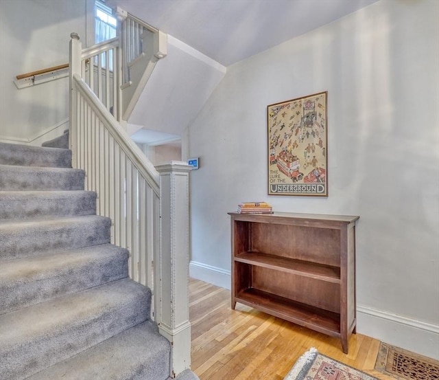 staircase featuring wood finished floors and baseboards