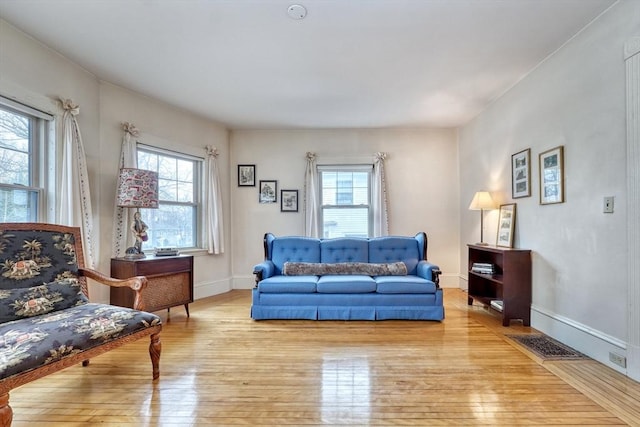 living area with a wealth of natural light, visible vents, light wood-style flooring, and baseboards