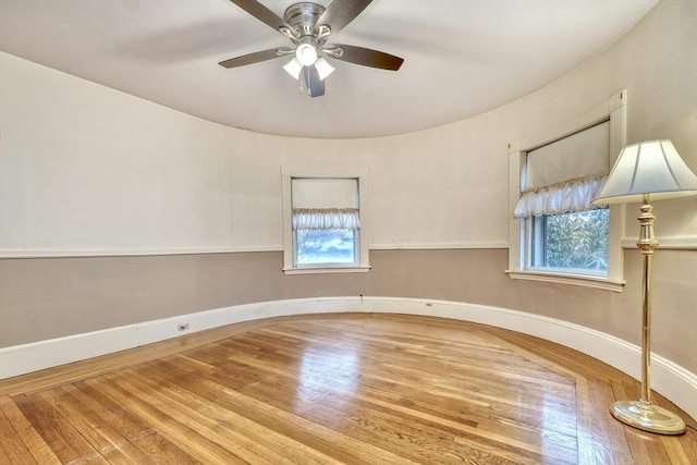 empty room featuring a ceiling fan, baseboards, and wood finished floors