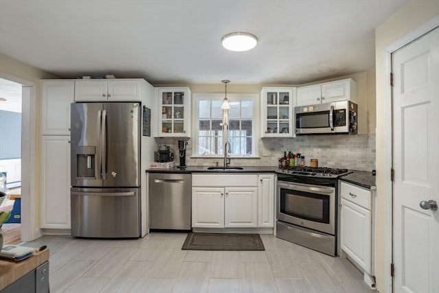 kitchen featuring dark countertops, white cabinetry, appliances with stainless steel finishes, and a sink