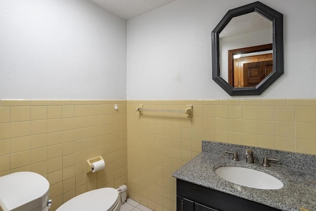 bathroom featuring toilet, a wainscoted wall, tile walls, and vanity