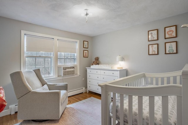 bedroom featuring a baseboard radiator, cooling unit, baseboard heating, and wood finished floors