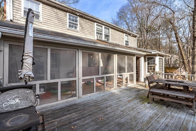 wooden deck featuring outdoor dining area and a sunroom