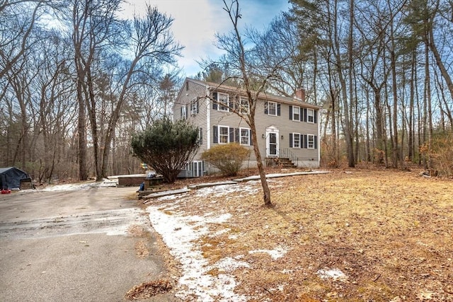 colonial-style house featuring aphalt driveway and a chimney