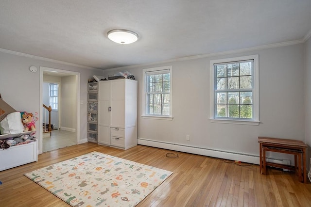 bedroom with baseboards, crown molding, hardwood / wood-style floors, and baseboard heating