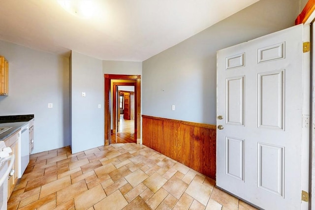 76 Belden St, Boston, MA 02125 - kitchen featuring a wainscoted wall, light stone finish floors, range, wood walls, and dark countertops