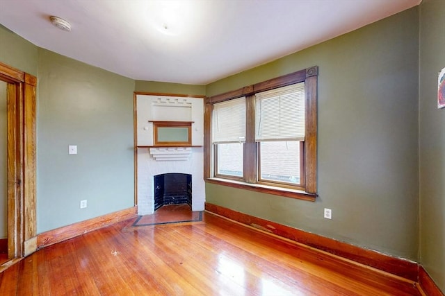 76 Belden St, Boston, MA 02125 - unfurnished living room with a brick fireplace, wood finished floors, and baseboards