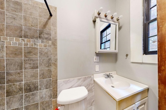 76 Belden St, Boston, MA 02125 - full bathroom with vanity, a tile shower, toilet, and tile walls