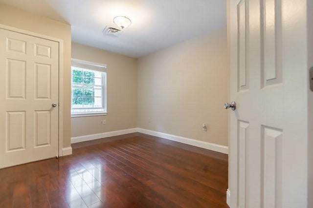 spare room with dark wood-style flooring and baseboards
