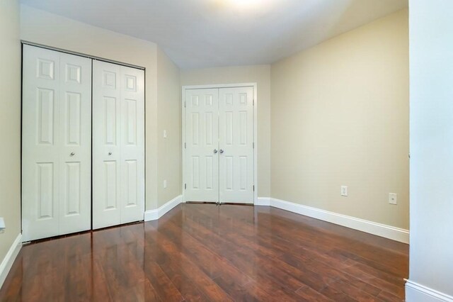unfurnished bedroom featuring dark wood-type flooring and baseboards