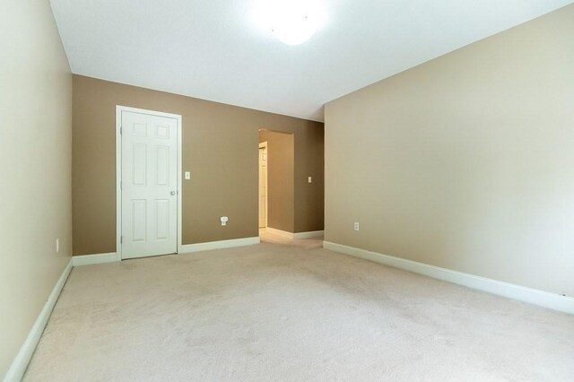 unfurnished room featuring light colored carpet and baseboards