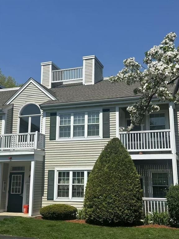 rear view of house with a balcony and a chimney