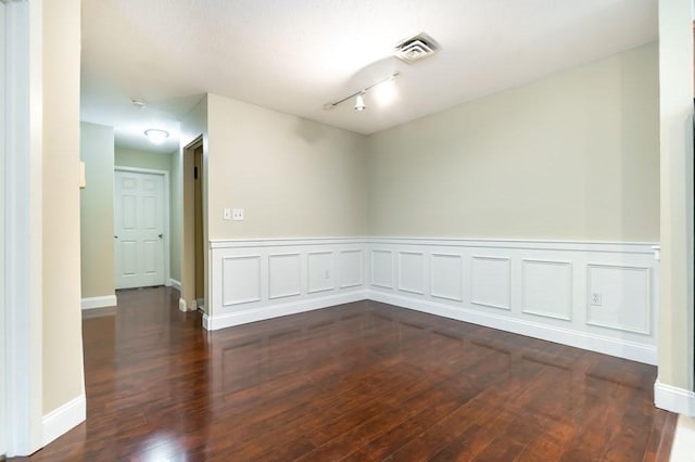 spare room with dark wood-style floors, wainscoting, and a smoke detector