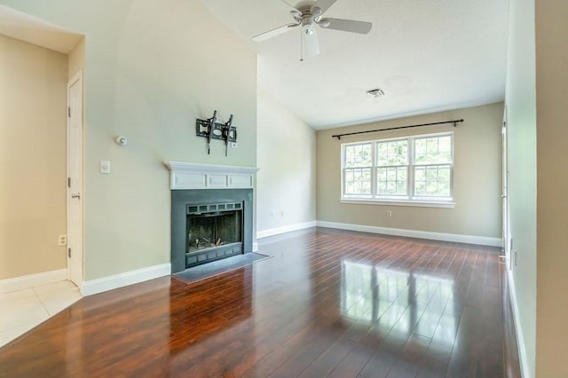 unfurnished living room with wood finished floors, a fireplace with flush hearth, ceiling fan, baseboards, and high vaulted ceiling