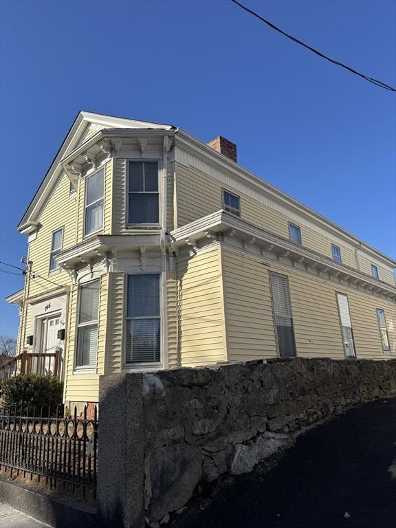 view of side of home featuring a chimney and fence