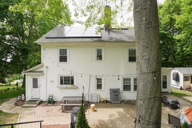 1013 Pleasant St, Worcester, MA 01602 - rear view of house with a patio area, roof mounted solar panels, and a shingled roof