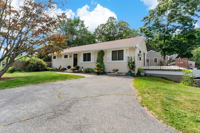 ranch-style home featuring aphalt driveway and a front lawn