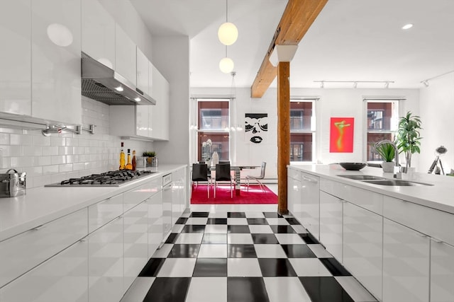 kitchen featuring stainless steel gas cooktop, a wealth of natural light, sink, and white cabinets