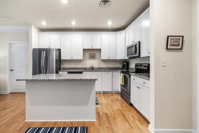 90 Trotter Rd Unit 309, Weymouth, MA 02190 - kitchen with stainless steel appliances, light wood-type flooring, a center island, white cabinets, and crown molding