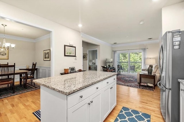 90 Trotter Rd Unit 309, Weymouth, MA 02190 - kitchen with freestanding refrigerator, light wood-type flooring, a kitchen island, white cabinets, and ornamental molding