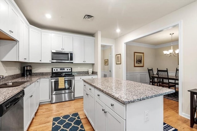 90 Trotter Rd Unit 309, Weymouth, MA 02190 - kitchen featuring stainless steel appliances, light wood-style flooring, a kitchen island, white cabinets, and a chandelier