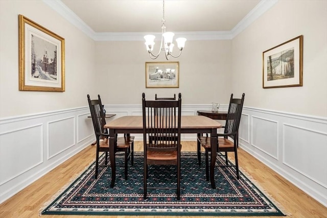 90 Trotter Rd Unit 309, Weymouth, MA 02190 - dining room featuring light wood-style flooring, crown molding, a chandelier, a wainscoted wall, and a decorative wall