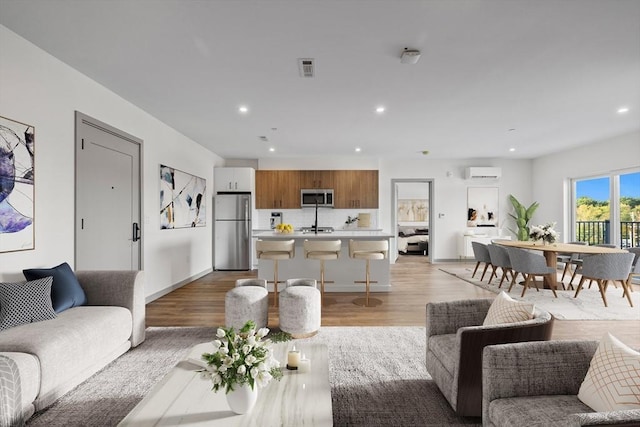 living room featuring an AC wall unit and light hardwood / wood-style floors