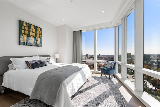 bedroom with expansive windows, multiple windows, and hardwood / wood-style flooring