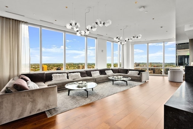 living room with a healthy amount of sunlight, light hardwood / wood-style flooring, a chandelier, and a wall of windows