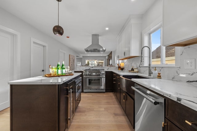 kitchen featuring appliances with stainless steel finishes, ventilation hood, pendant lighting, white cabinets, and light hardwood / wood-style floors