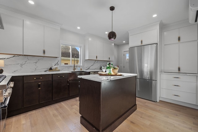 kitchen featuring decorative backsplash, a center island, light hardwood / wood-style floors, and stainless steel refrigerator