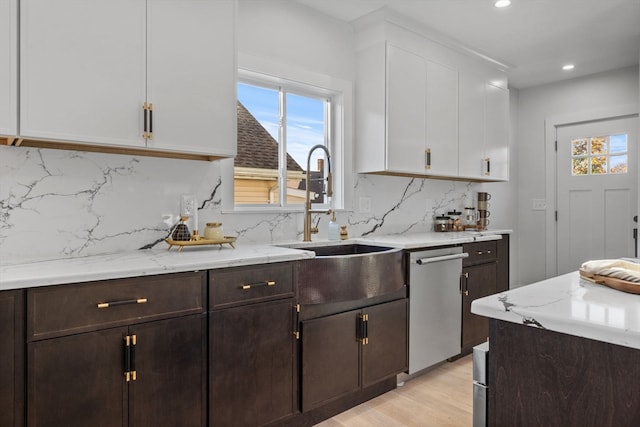 kitchen with tasteful backsplash, stainless steel dishwasher, dark brown cabinetry, light hardwood / wood-style floors, and white cabinetry