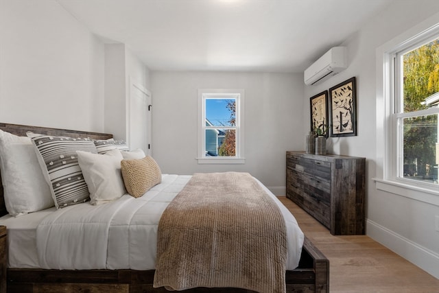 bedroom featuring light hardwood / wood-style floors and an AC wall unit