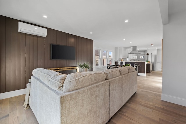 living room featuring wood walls, light hardwood / wood-style floors, and an AC wall unit