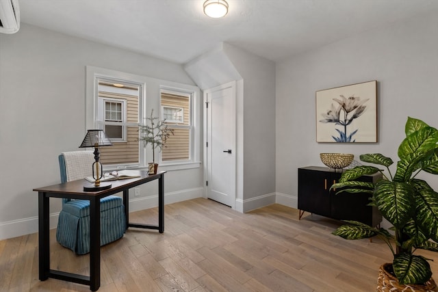 office space featuring a wall mounted air conditioner and light wood-type flooring