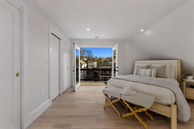 bedroom with access to exterior, light hardwood / wood-style floors, and vaulted ceiling